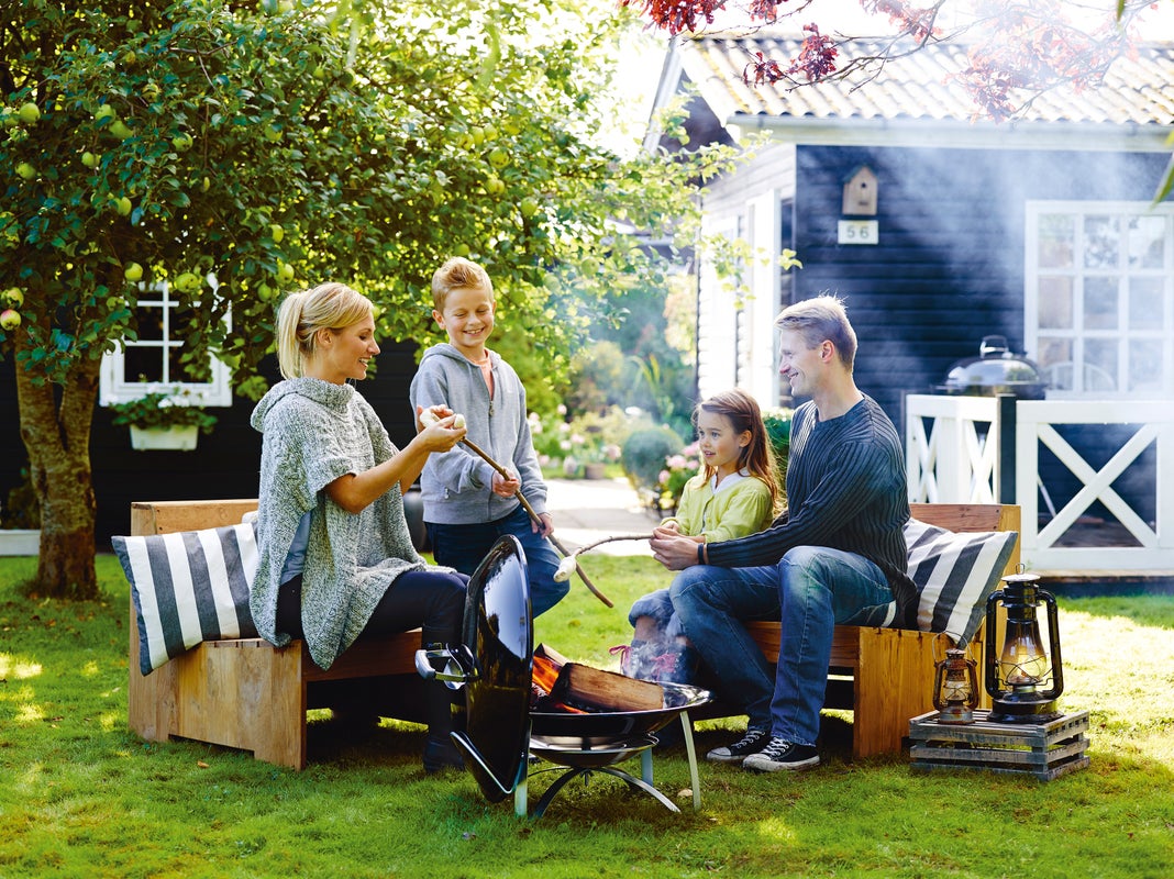 una famiglia con due bambini con il caminetto mobile da giardino weber